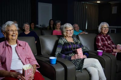 Residents enjoying a movie with popcorn in an activity room