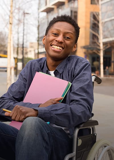 Young resident in a wheelchair outside the facility
