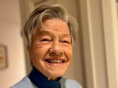 A smiling elderly woman in a bright setting
