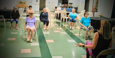 Residents participating in a seated exercise class in a common area