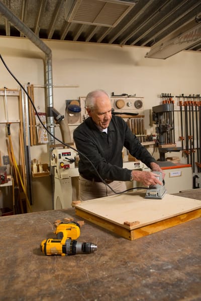 An elderly man working in a woodworking shop