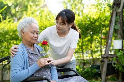 A staff member giving a flower to a resident in a garden