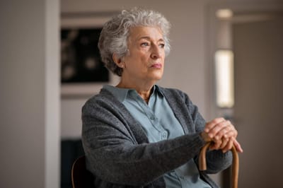 A thoughtful senior woman sitting in a cozy interior space