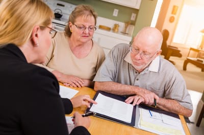 Senior couple discussing with a staff member at a table