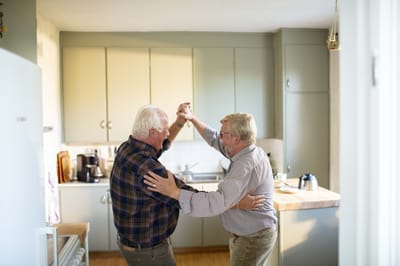 Two men dancing joyfully in a kitchen