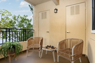 A cozy outdoor balcony with seating and greenery