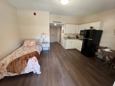 Cozy resident room with bed, kitchenette, and seating