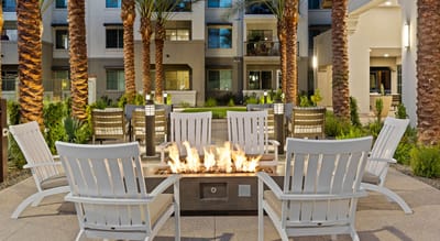 Outdoor seating area with fire pit surrounded by palm trees