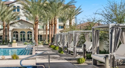 Outdoor pool area with cabanas and palm trees