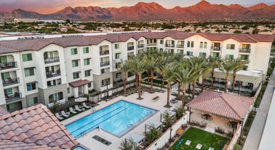 Aerial view of a senior living facility with pool and palm trees