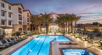 Outdoor pool area with palm trees and building in background