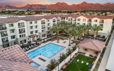 Aerial view of a senior living facility with a pool and palm trees