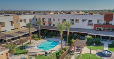 Aerial view of a senior living facility with a pool and landscaped areas