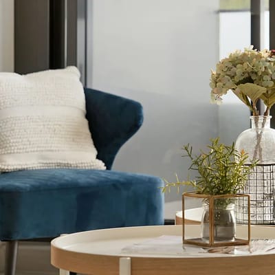 Cozy lounge area with a blue chair and vase