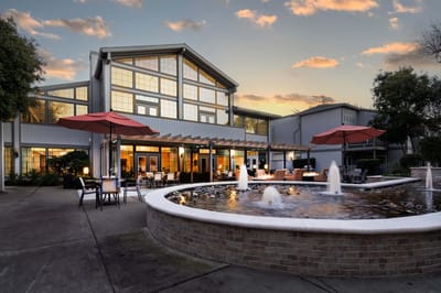 Exterior view of a senior living facility with a fountain and seating areas