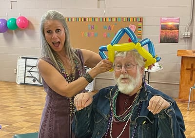Resident enjoying a fun balloon hat activity with staff