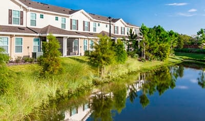 Exterior view of Village Park Senior Apartments by a pond.