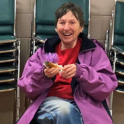 Smiling resident holding craft materials indoors