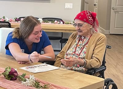 Staff member assisting a resident with a game in the lounge
