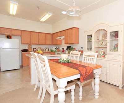 Bright dining area with wooden table and kitchen in background