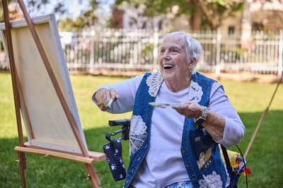 Senior resident painting outdoors in a garden setting