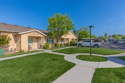 Exterior view of Arbor Faire Senior Apartments with green landscaping
