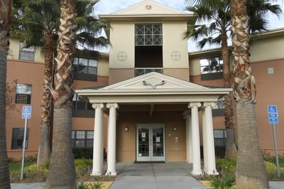 Front entrance of Ahepa 302 Apartments with palm trees