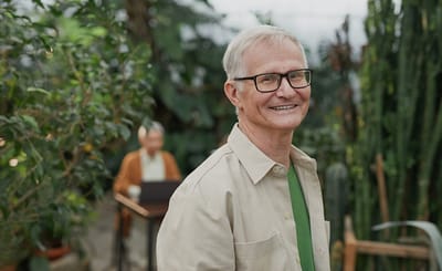 A resident smiling in a greenhouse setting