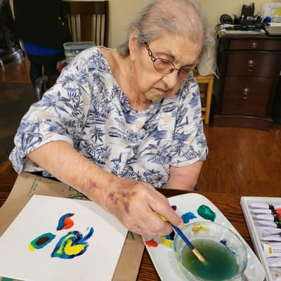 Resident painting at a table in an indoor activity