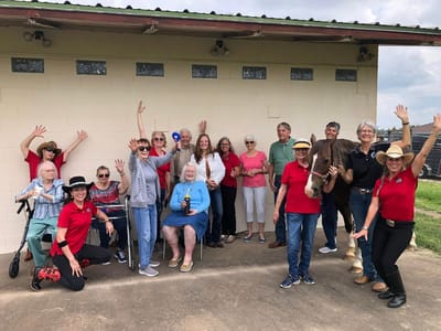 Residents and staff celebrating with a horse outdoors