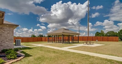 Outdoor shaded area with picnic tables and grassy space