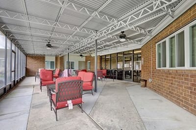 Outdoor seating area with red chairs under a covered patio