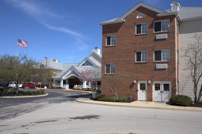 Building exterior of a senior living facility with trees and parking