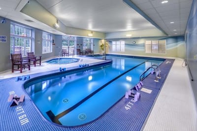 Indoor pool area with a jacuzzi and seating