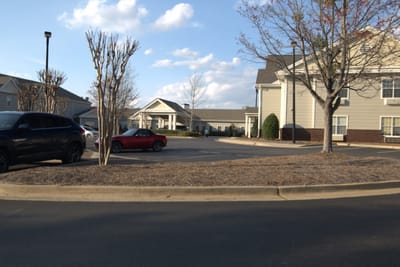 Parking area with resident vehicles and the facility entrance in the background