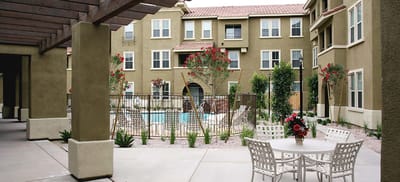 Outdoor seating area with pool and buildings in background
