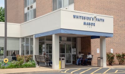Entrance of Whiteside's Faith Manor with residents seated outside