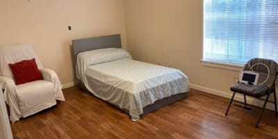 Bright, simple private room with a bed and chair