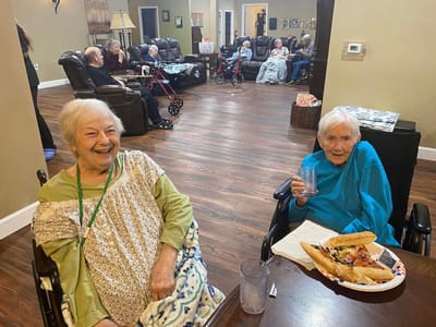 Two smiling residents enjoying food in a common area