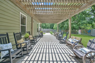 Outdoor patio area with rocking chairs and greenery