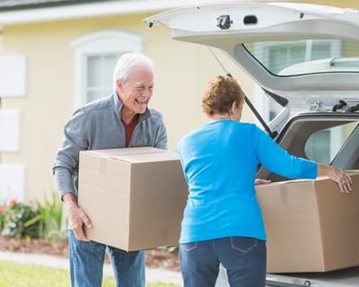 Two seniors unloading boxes from a vehicle