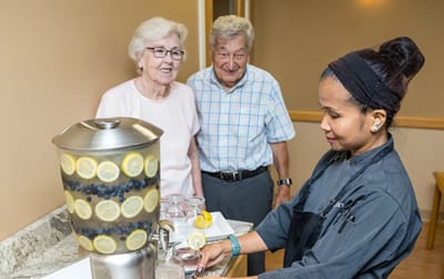 Resident enjoying refreshments with staff in the lounge