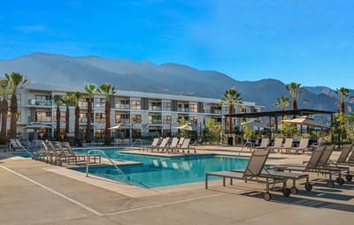 Outdoor pool area with palm trees and mountains in the background
