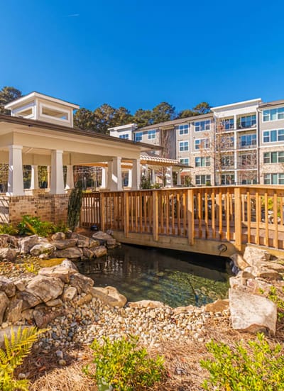 Outdoor view of a bridge over a pond with landscaping