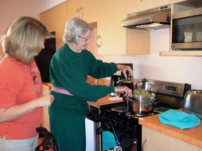 Resident cooking in a kitchen with staff assistance