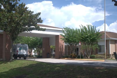 Exterior view of a senior care facility with a van and trees