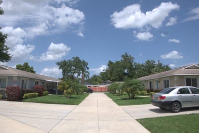 Exterior view of Kare Assisted Living with gardens and vehicles