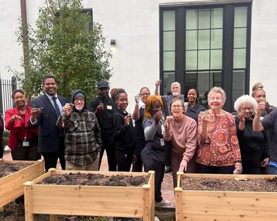 Residents and staff in a garden area holding seedlings