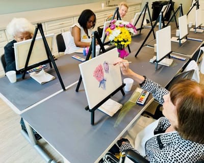 Residents participating in a painting activity in an activity room