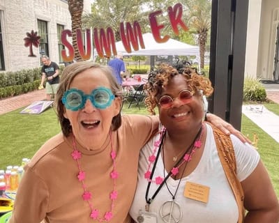 Two women wearing festive glasses at a summer event